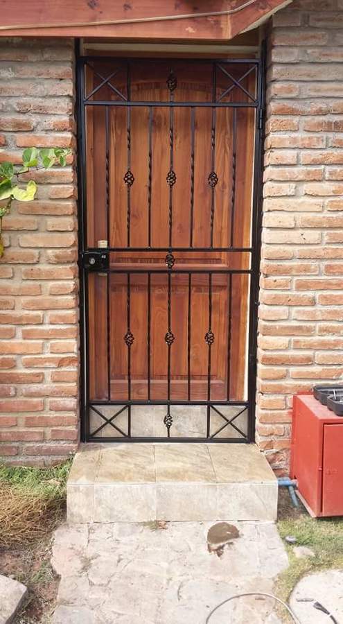 proteccion de puerta con adornos de piñas forjadas