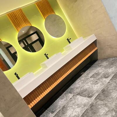 Baño moderno con mesón triple, espejos LED y revestimientos de madera.