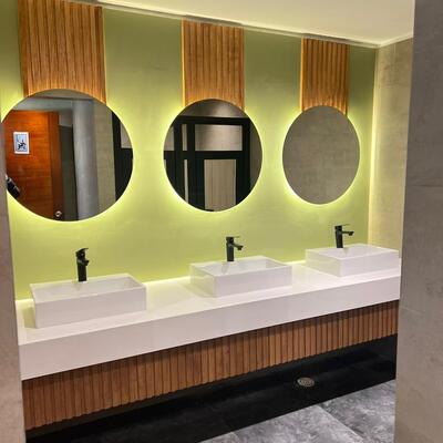 Baño terminado — mesón, espejos retroiluminados y revestimiento en madera